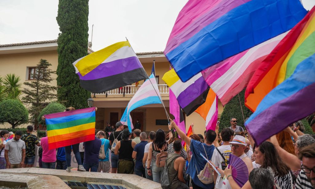 People hold up a variety of colourful flags symbolising different parts of the LGBTQ+ community during a rally in Spain against anti-LGBTQ+ policies perpetuated by the right-wing group Vox ahead of the general election