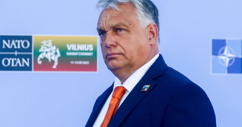 Hungary's prime minister Viktor Orbán, who has led an anti-LGBTQ+ regime, wears a white shirt, orange tie and blue jacket as he stares somewhere off camera