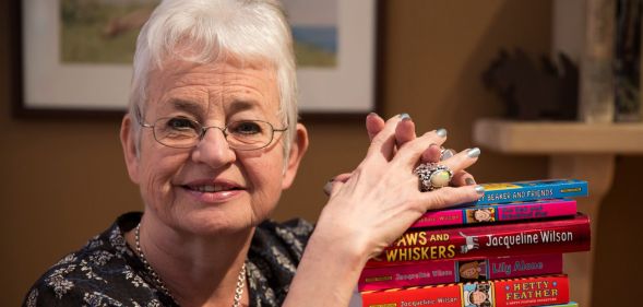 Jacqueline Wilson resting her hands on a pile of her books.