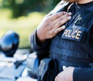 A police officer wearing a vest stood by a police car.