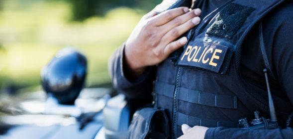 A police officer wearing a vest stood by a police car.