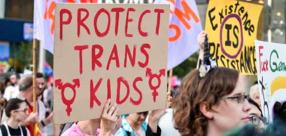 Protester holds up a sign reading "protect trans kids"