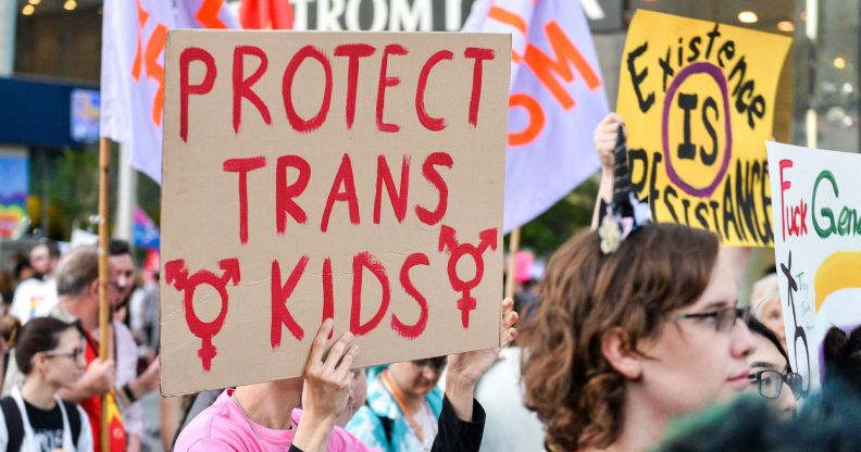 Protester holds up a sign reading "protect trans kids"