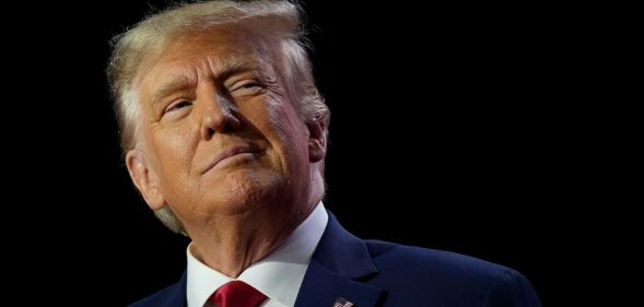 Donald Trump wears a white shirt, red tie and blue jacket as he stares somewhere off camera