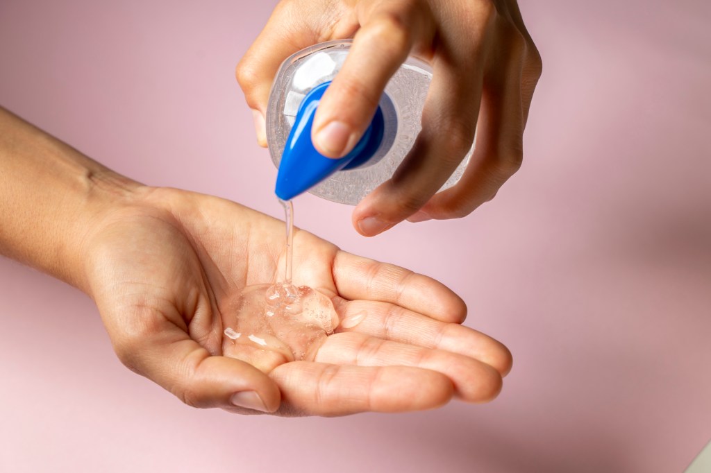 A person pumping clear liquid from a bottle into their hand