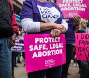 An activist seen holding a placard that says protect safe, legal abortion