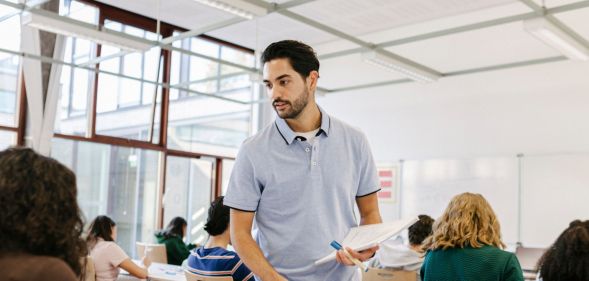 Photo of a teacher standing in a classroom surrounded by secondary age students