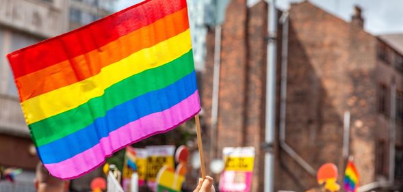 A person holds up a Pride flag during a protest.