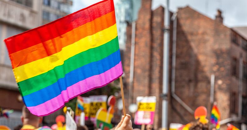 A person holds up a Pride flag during a protest.