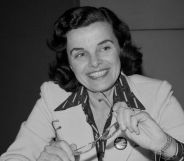 A black and white picture of Dianne Feinstein smiling as she holds a pair of glasses.