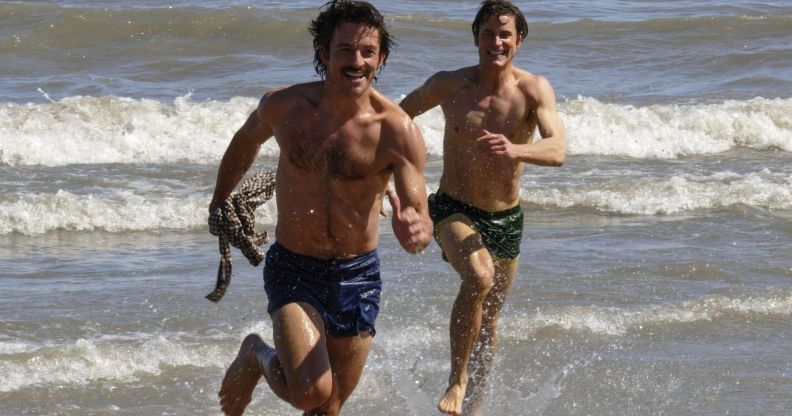 Jonathan Bailey and Matt Bailey chase each other on a beach in a still from Fellow Travelers.