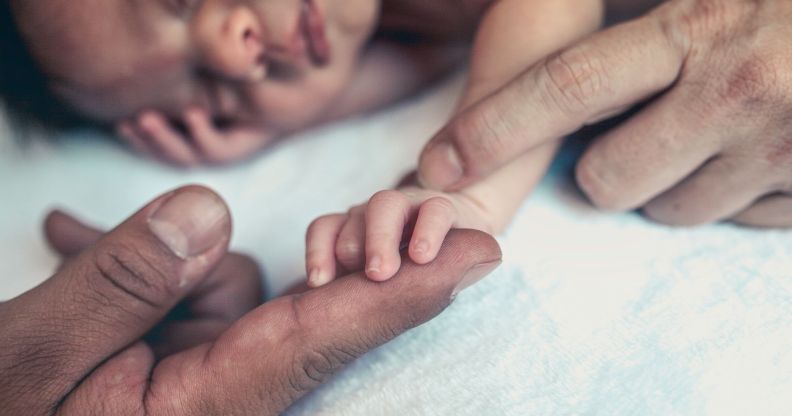 Stock image of newborn baby's hand holding the finger of their parent