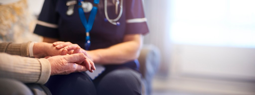 A nurse holds a patient's hand. 