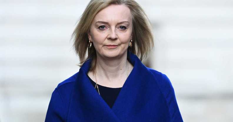 Liz Truss pictured walking outdoors wearing a blue jacket.