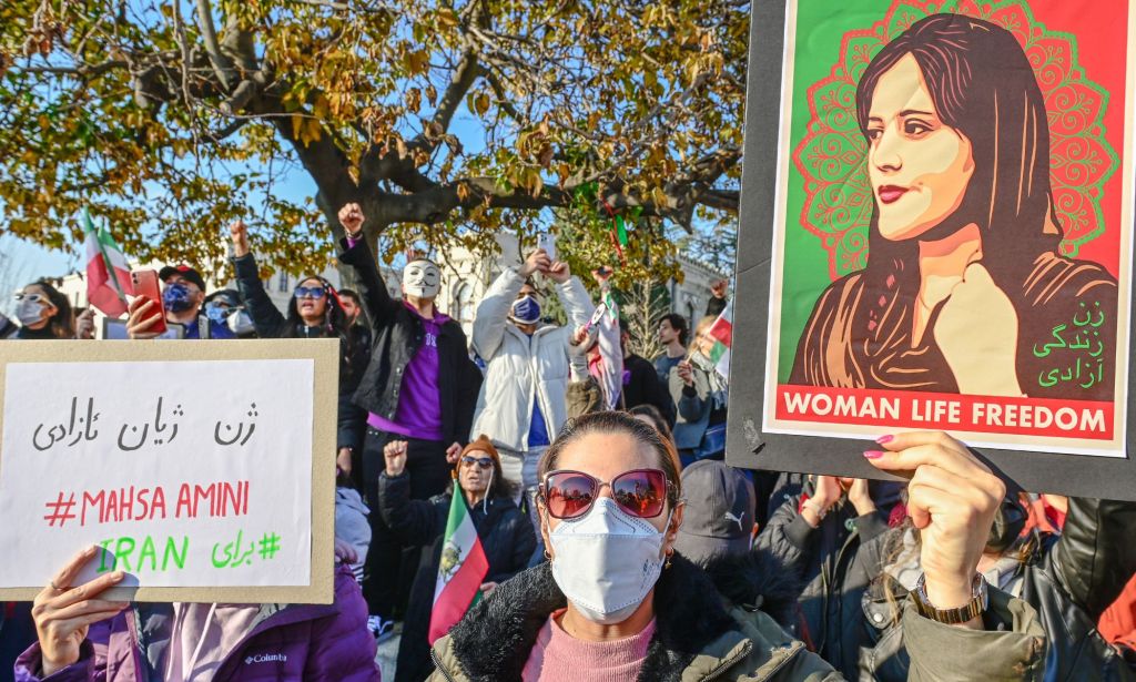 A person holds up a sign reading 'Woman. Life. Freedom' with a picture of Iranian-Kurdish woman Mahsa Amini, who was killed in September 2022. Protests, led by women and LGBTQ+ people, erupted in Iran afterwards