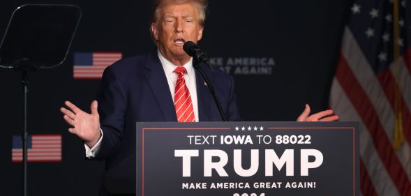 Donald Trump stands behind a podium reading "Trump"