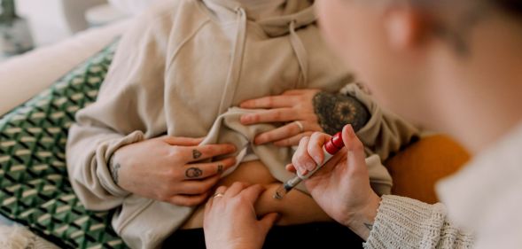 A couple uses a needle to inject the others stomach as part of an IVF treatment.