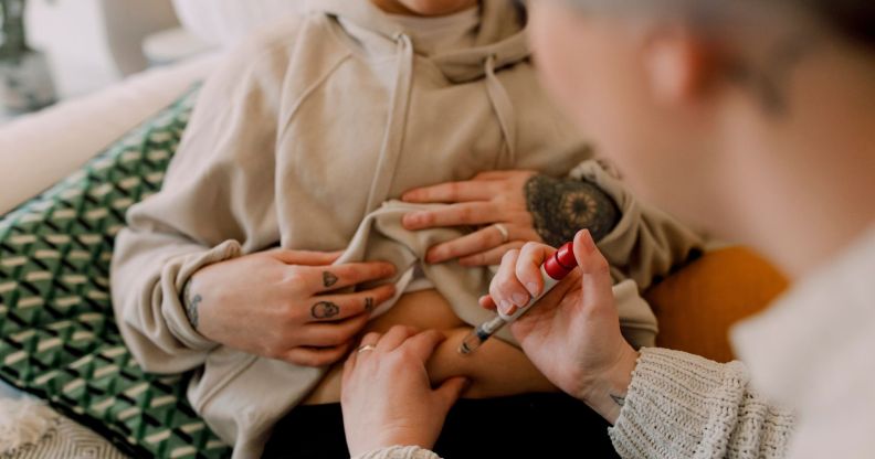 A couple uses a needle to inject the others stomach as part of an IVF treatment.