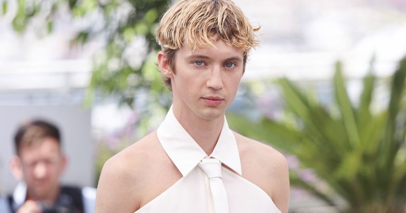 Troye Sivan in a white shoulder-less shirt.