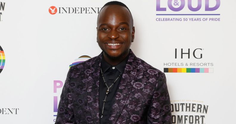 Will Njobvu in a patterned black and purple suit.