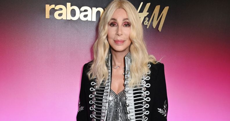 Pop singer Cher wears a silver corset type top with a silver, grey and black jacket and long blonde hair