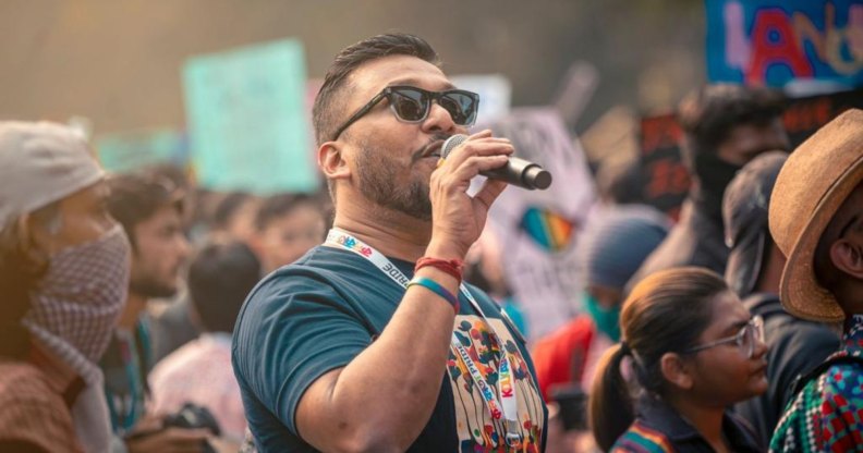 Navonil Das, an LGBTQ+ activist from India, pictured speaking into a microphone at a demonstration.