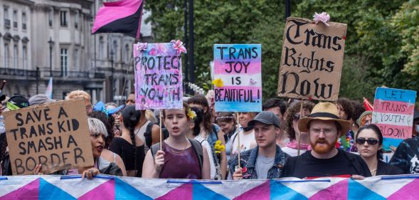 Various people hold up signs calling for trans youth and adults to be protected amid repeated attacks on healthcare rights, closure of gender identity services in England and more in the UK