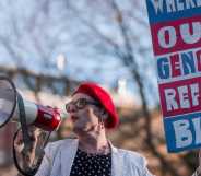 Activist Sarah Jane Baker holds a sign reading "where's our gender reform bill?" and speaks into a bullhorn