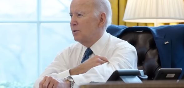 Joe Biden rolling up his sleeves whilst sat at the White House desk.