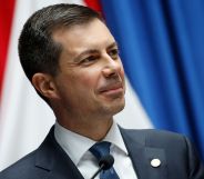 Pete Buttigieg smiling while on the stand of a press conference stage.