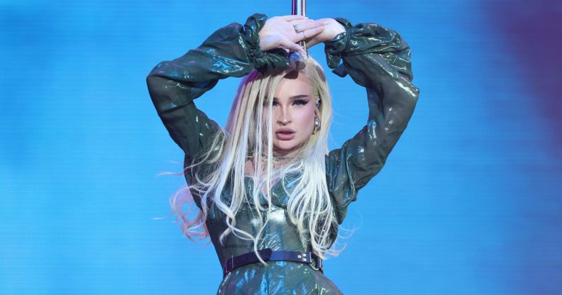 Kim Petras wears a sparkly outfit onstage as she holds a microphone above her head