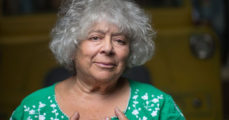 Actor Miriam Margoyles wears a green shirt with while spots on it while her hands cover her chest over her heart