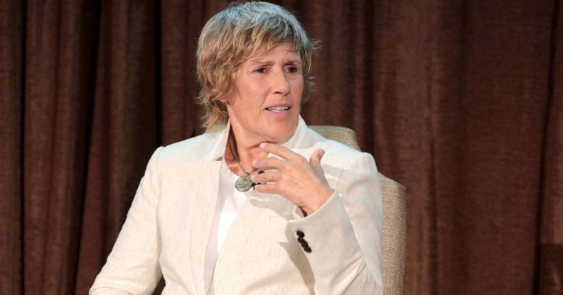 Lesbian swimmer Diana Nyad wears a cream suit while speaking on stage