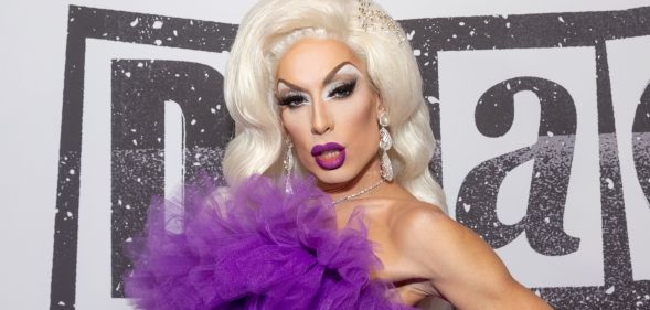 Drag Race star Alaska wears a purple dress and blonde wig.