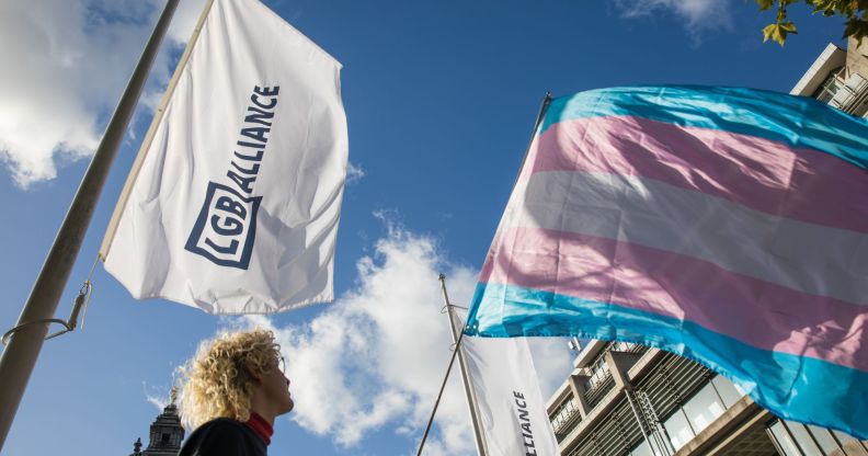 Image of protester waving a trans flag alongside the LGB Alliance flag