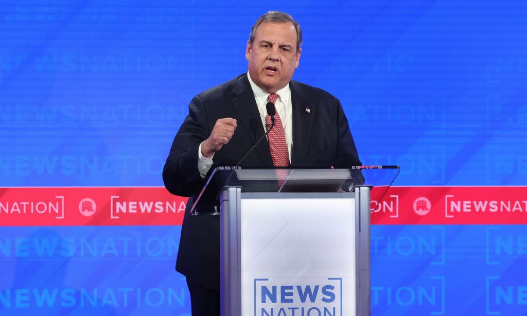 GOP presidential hopeful Chris Christie wears a suit and tie as he stands at a podium for the Republican debate, where he made several anti-trans statements